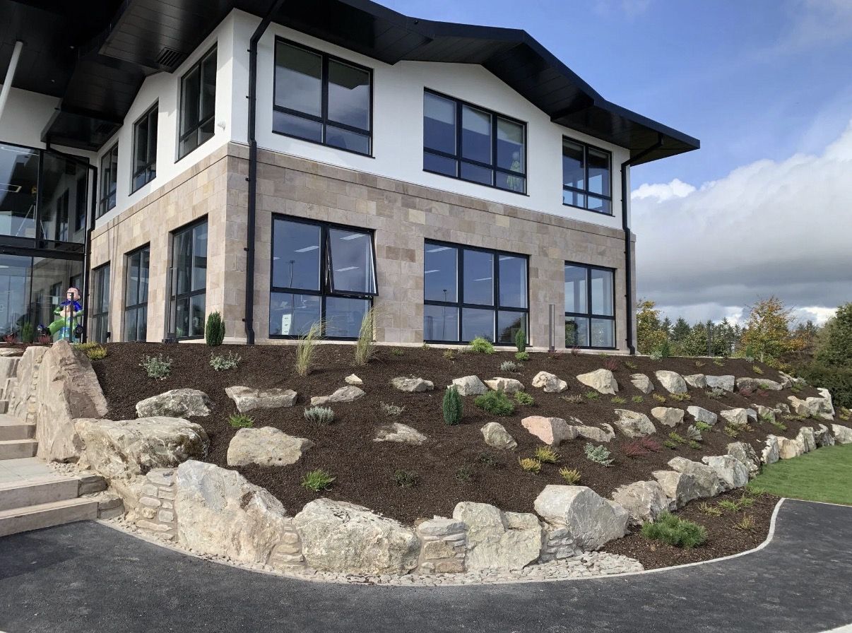 Boulder retaining slope with mulch and planting at a commercial building