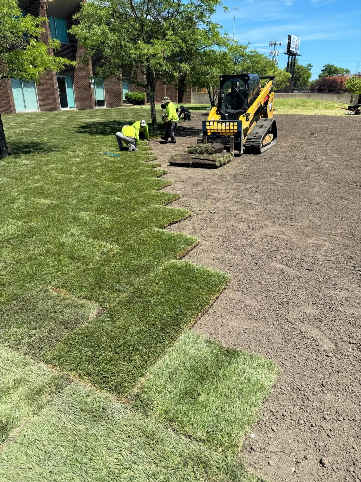 Crew laying sod beside a commercial office building